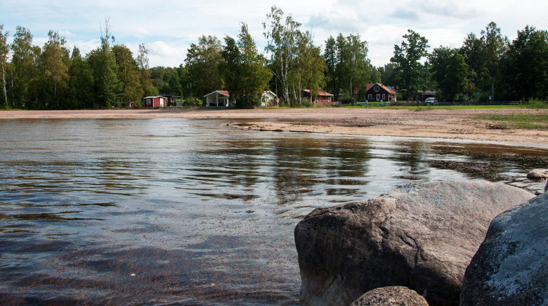 Fagersannabadet. Fotot är taget från en stor sten i vattnet och bakgrunden syns strandkant, träd och några stugor.