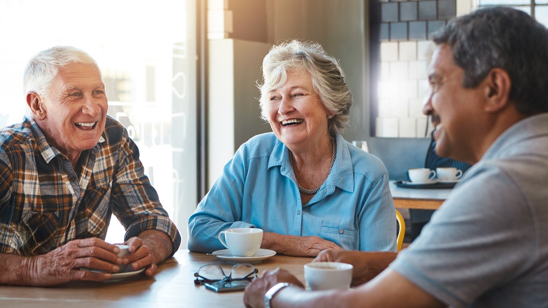 En grupp seniorer har det trevligt tillsammans över en kopp kaffe.