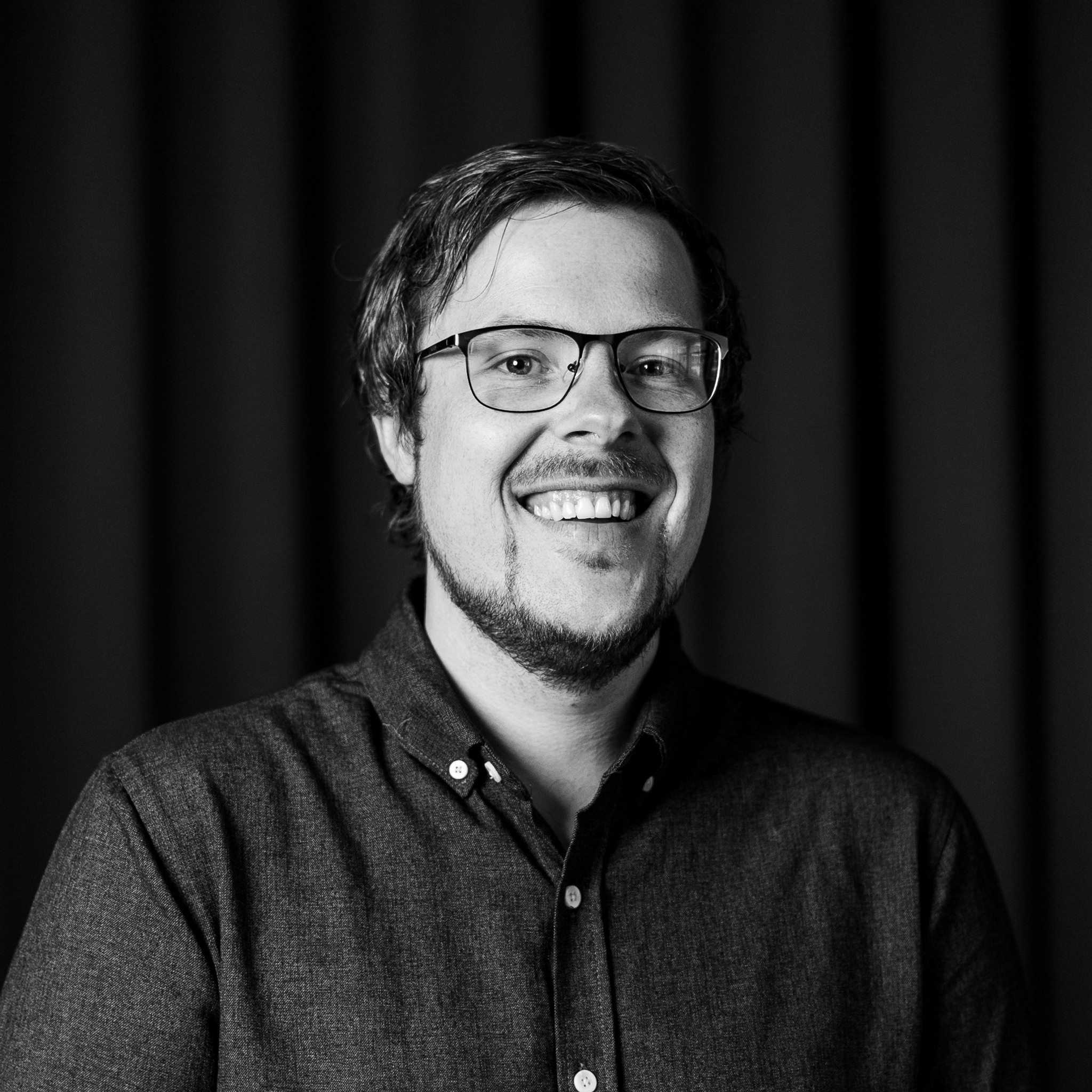 Ett svartvitt foto av en leende man.