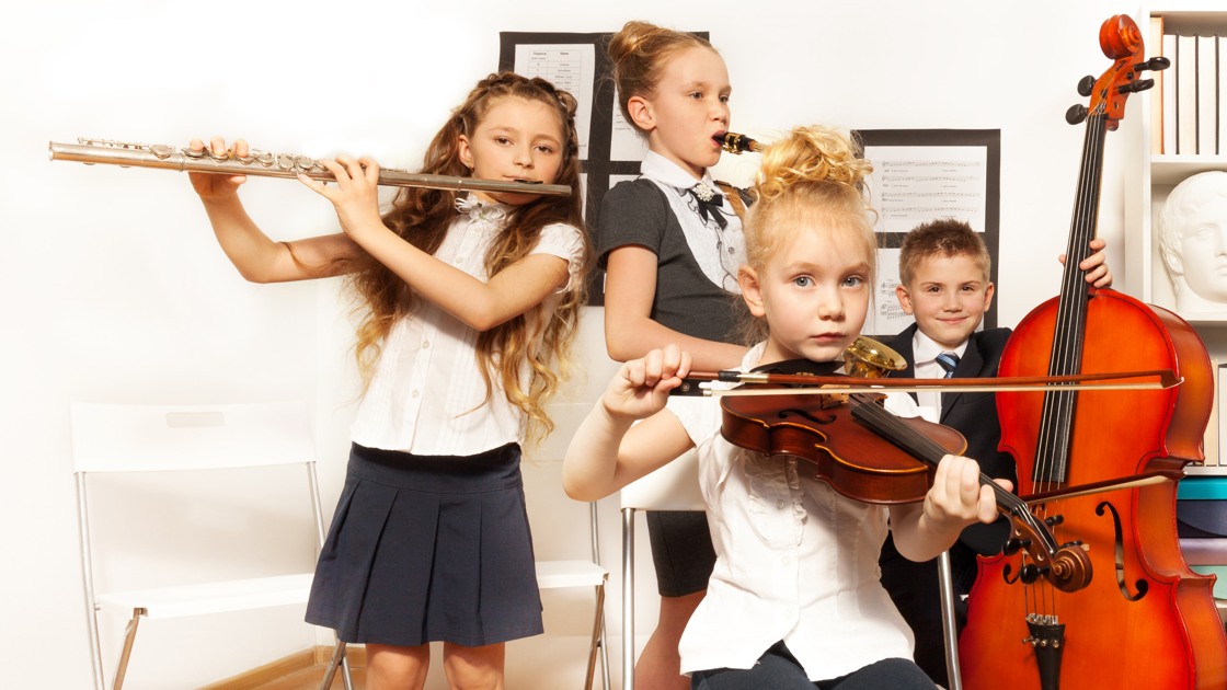 Skolbarn spelar musikinstrument tillsammans på skolkonsert.