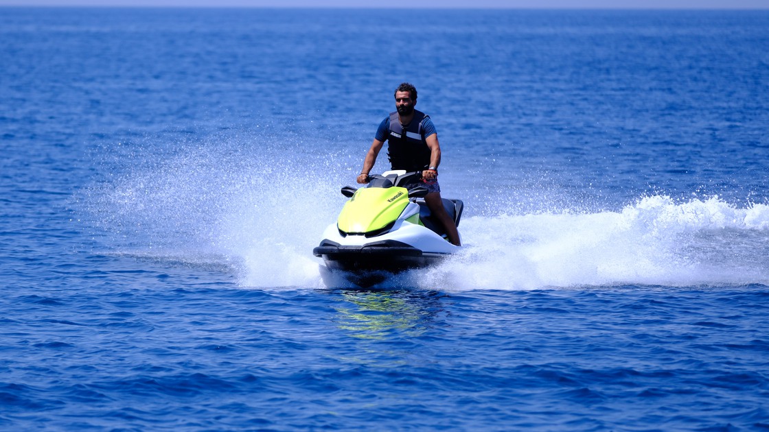 Young man with beard riding jet-ski in a sunny summer day