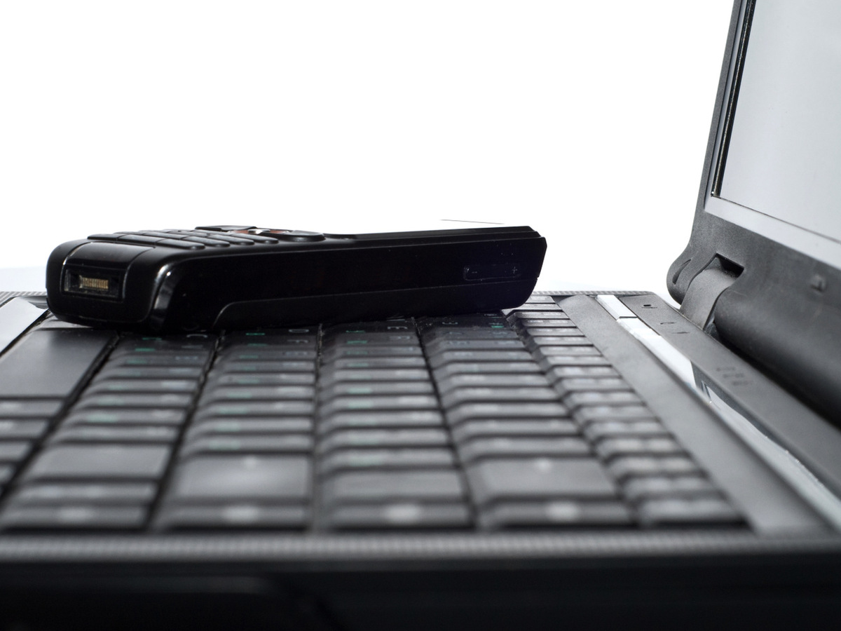 En laptop med en mobil som ligger på tagentbordet