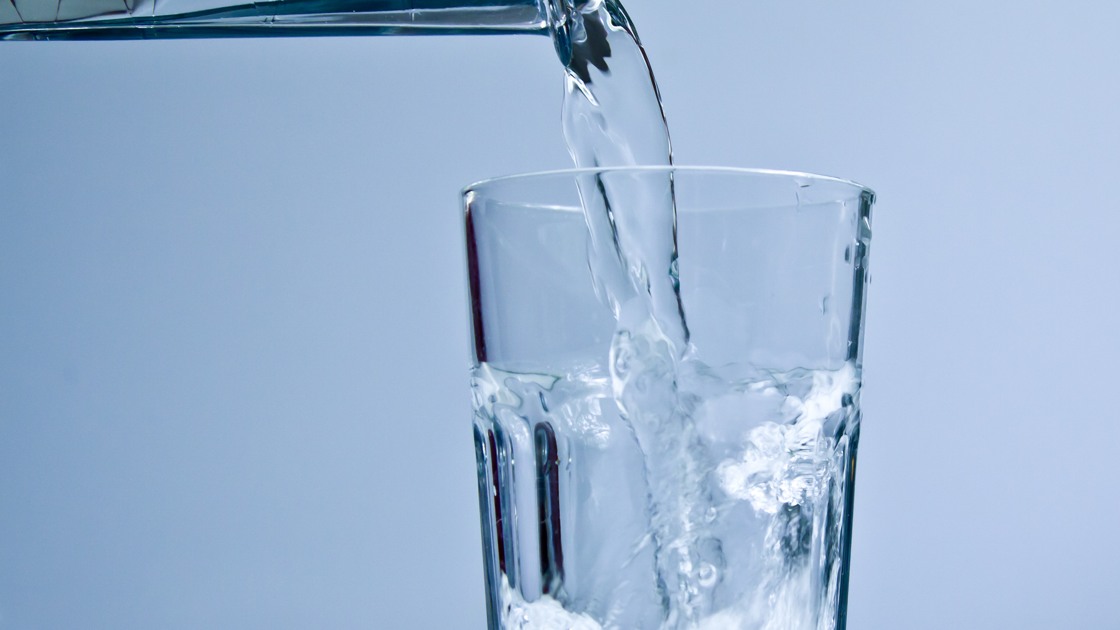 Vatten som rinner ur en kran ned i ett glas.