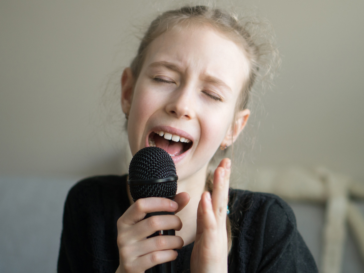 Cute little girl singing karaoke at home.