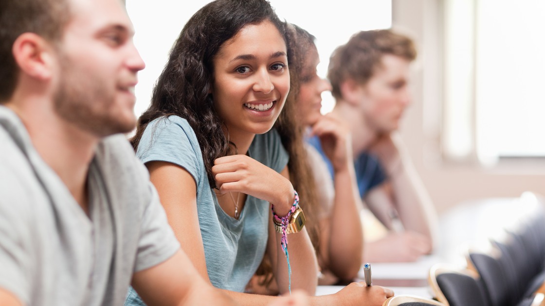 Smiling students listening a lecturer in an amphitheater