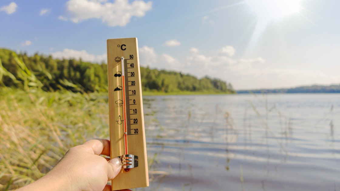 Termometer som visar 30 grader framför en sjö