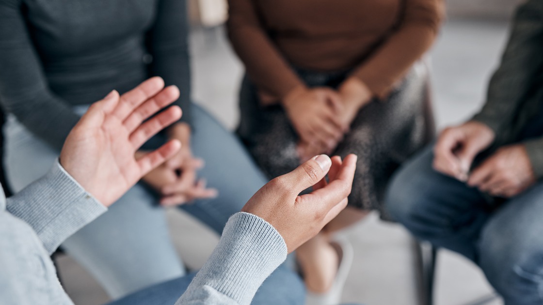 Support with group, therapy and mental health with hands and help, people together talking about problem and crisis. Psychology, healthcare and trust, respect and community in counseling for trauma.