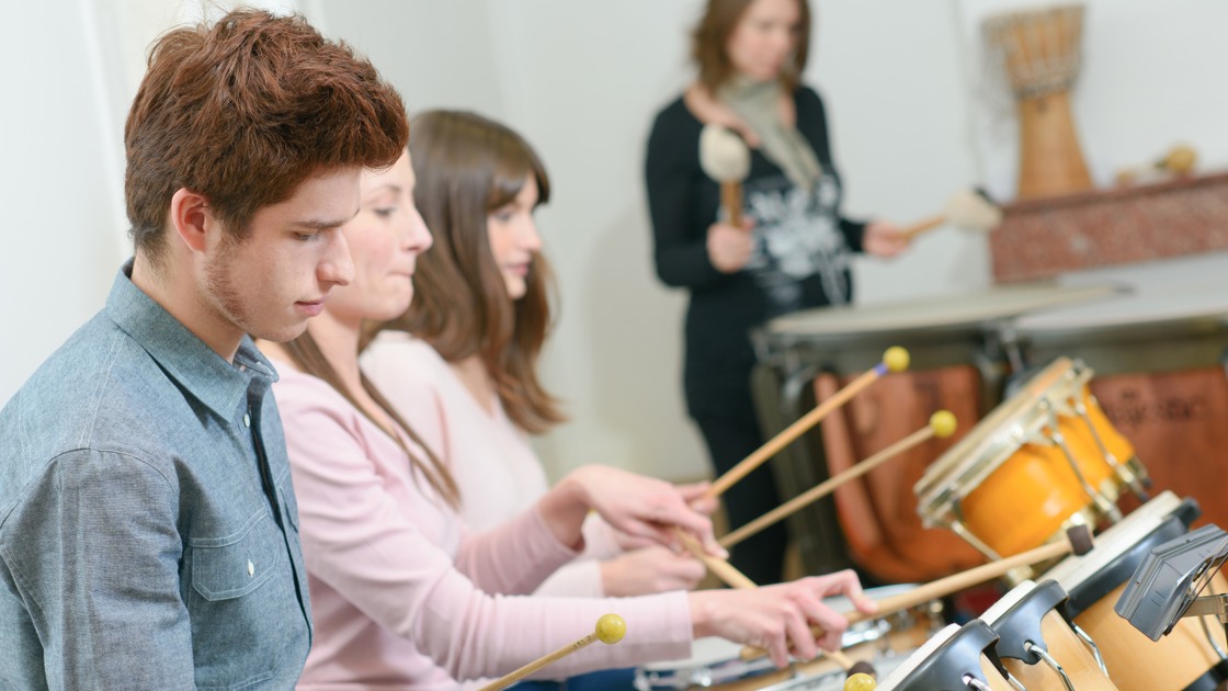 Unga människor under uppträdande spelar på trummor.