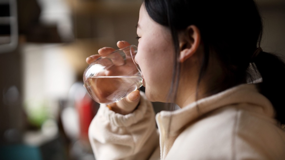 Kvinna dricker vatten ur ett glas