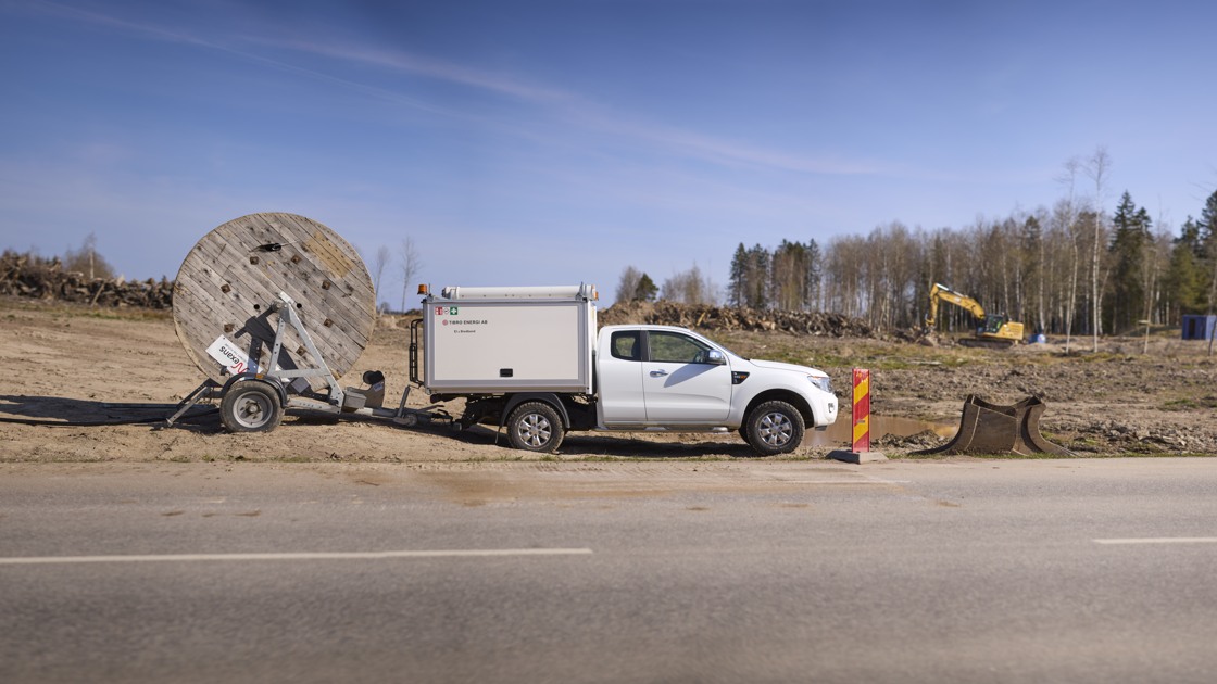 En vit bil från Tibro energi står parkerad vid vägkanten.