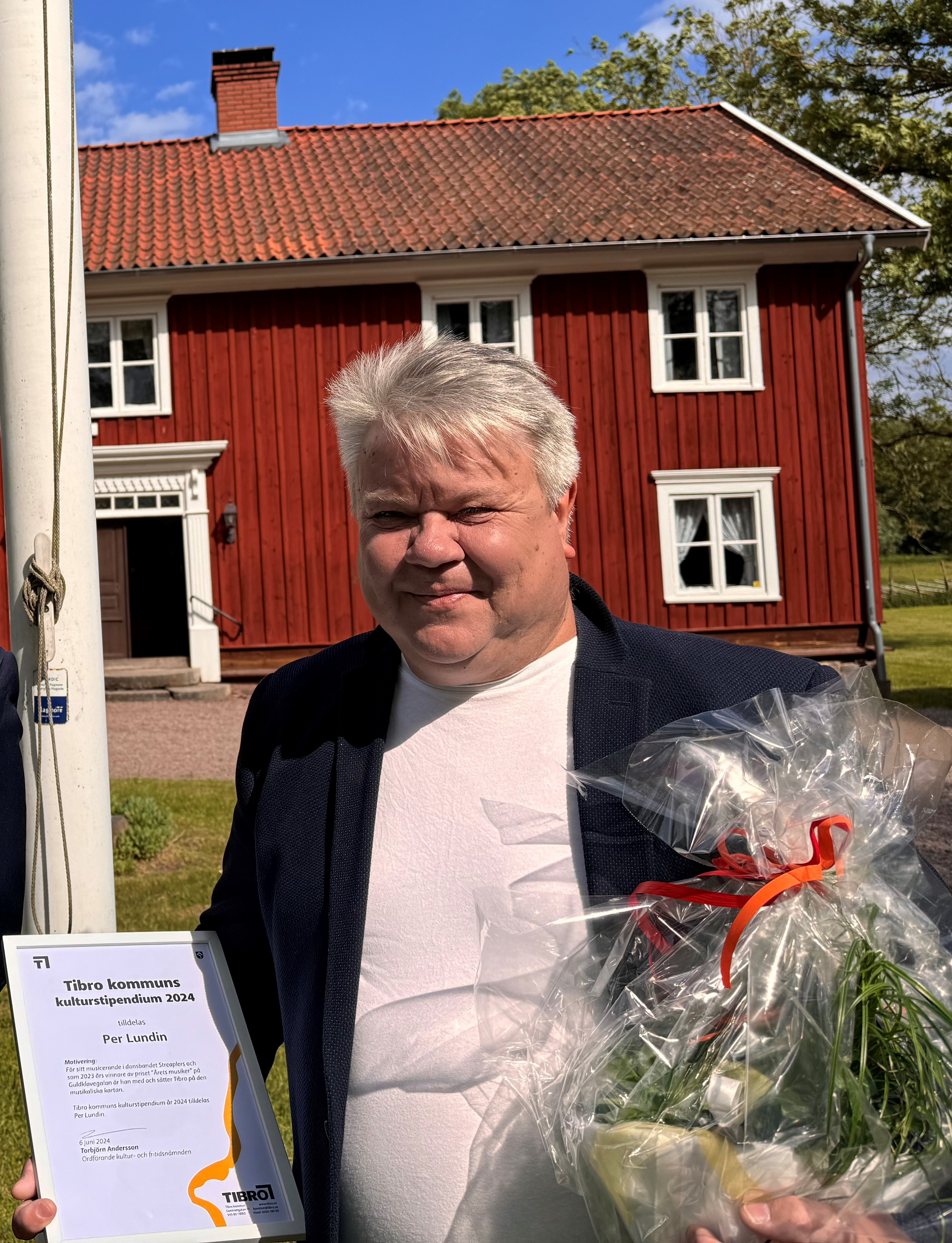 Fotot visar Per Lundin hållandes i blommor och ett diplom