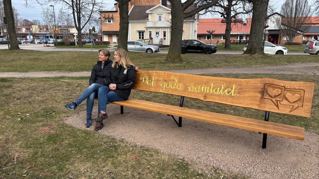 Två kvinnor sitter och samtalar på vänskapsbänken Det goda samtalet framför kommunhuset. 