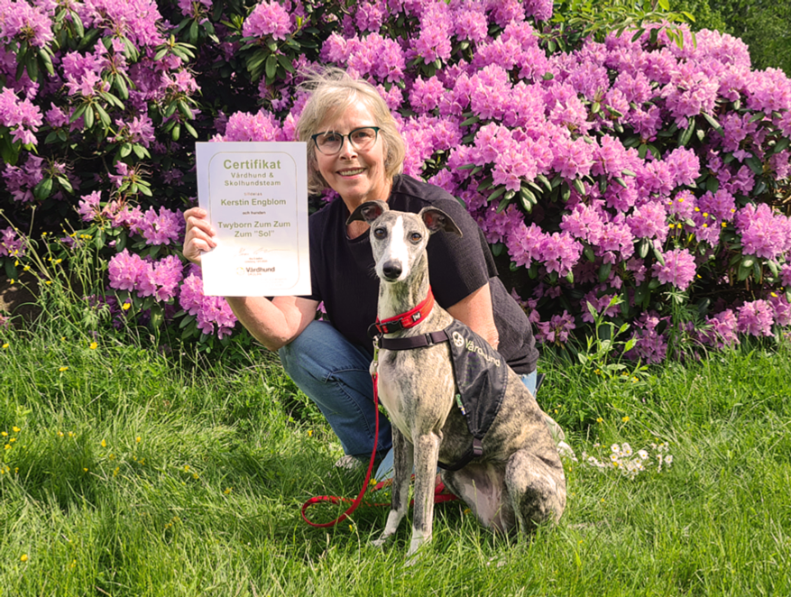 Kerstin Engblom visar upp certifikatet, tillsammans med sin hund Sol.