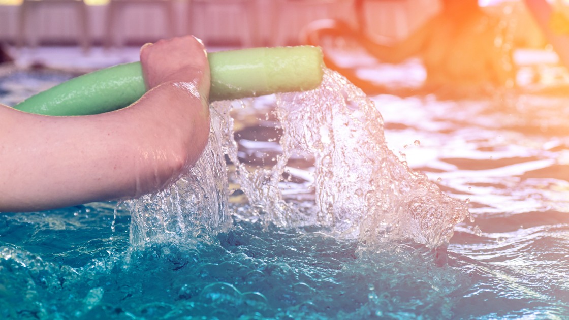 Personer tränar vattengymnastik i en pool.