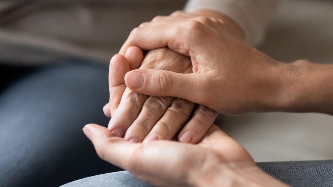 Close up young woman holding female hand of older mother, caring adult grown up daughter supporting and comforting mature mum, expressing love, two generations trusted relations