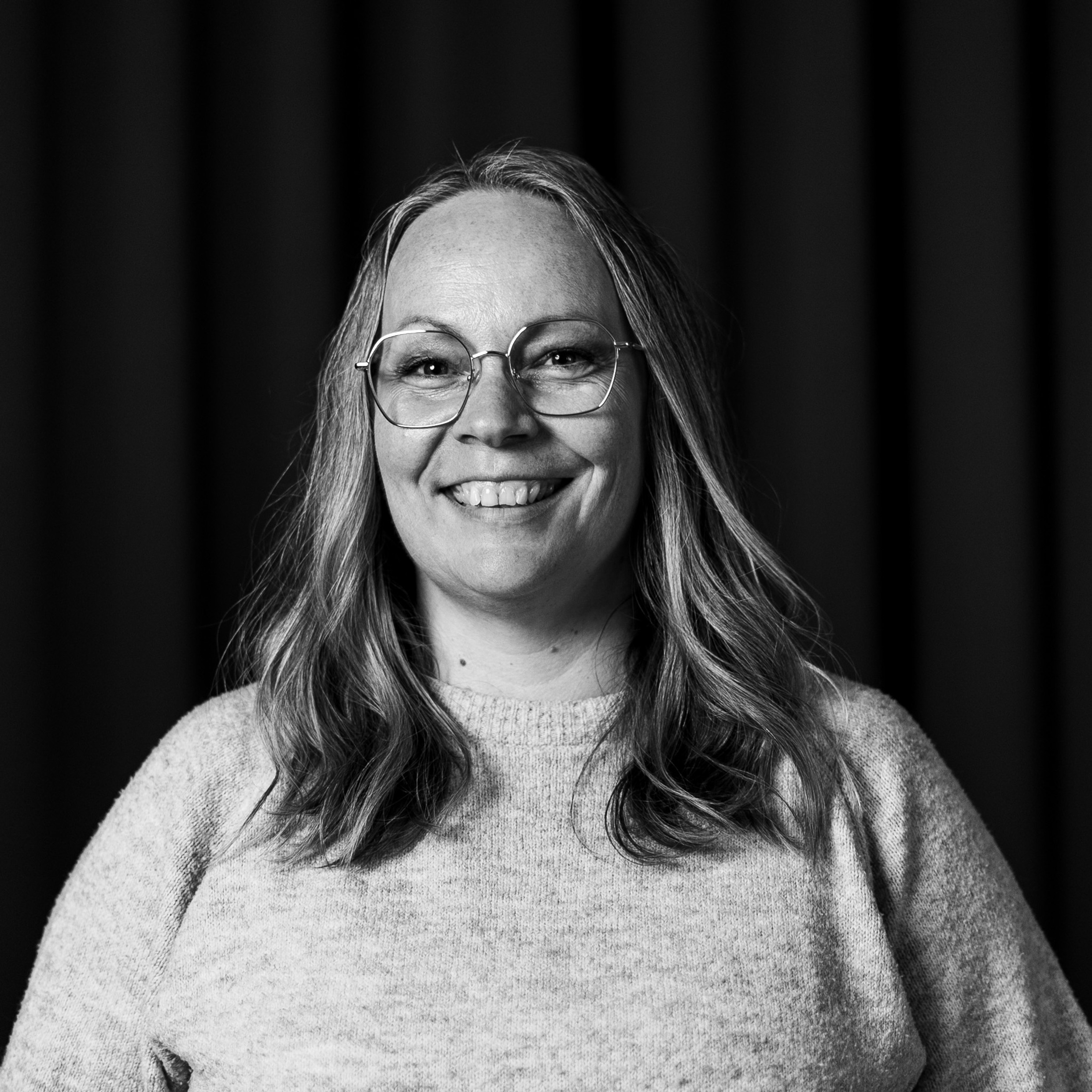Ett svartvitt foto av en kvinna som bär glasögon.