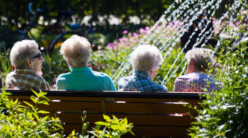 Sittande pensionärer i en park.