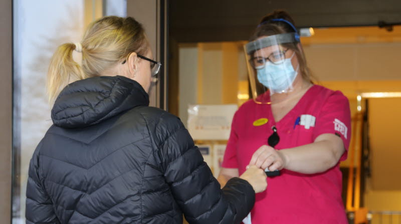 Personal förser besökare med visir och munskydd på Bäcklidens äldreboende