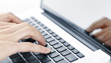 Närbild på händer som skriver på en dator.