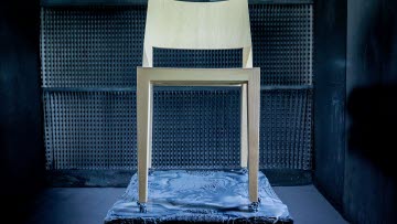 En trä stol som står i ett lackeringsbås i en möbelfabrik
