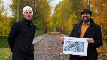 Plan- och byggchefen Kim Olsson och stadsarkitekten Leif Ahnland  står med förslaget till ny centrumutvecklingsplan vid järnvägsövergången i centrala Tibro.