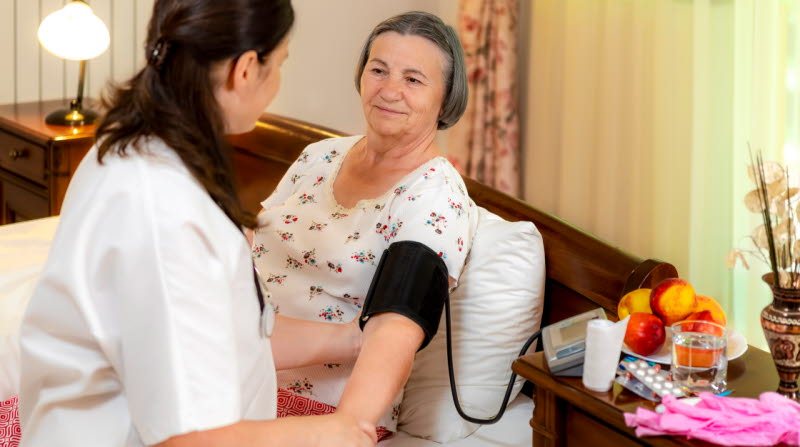 Omvårdnadspersonal som tar blodtryck på äldre kvinna