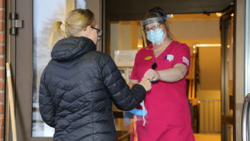 Personal förser besökare med visir och munskydd på Bäcklidens äldreboende